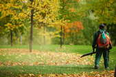 A man uses an electric leaf blower.