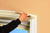 A person painting window trim with white paint.