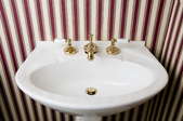 White porcelain sink in a bathroom with red striped wallpaper.