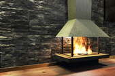 free standing metal fireplace in front of stone wall