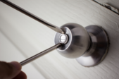 silver interior doorknob touched by the tips of two screwdrivers