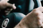 hands gripping steering wheel while driving car