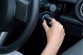 A hand turning a key in a car's ignition switch.