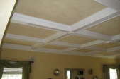 white beams surrounded by trim on tan ceiling