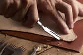 hands cutting leather with a special curved tool