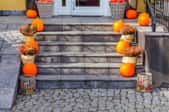Pumpkins and bushels of apples adorning the stone front steps of a house.