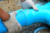 A man adjusts blue plastic pipes.