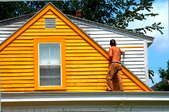 A house in Maine being painted yellow on top of its original white.