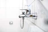 A new bathtub faucet with a chrome finish in a white bathroom.