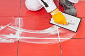 A person lays grout between red floor tiles.