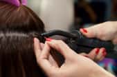 A salon stylist adding in hair extensions.