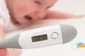 closeup of a thermometer with a baby in the background