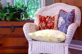 A cane chair with pillows on it.