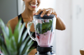 woman making a smoothie in a blender