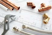 Copper joints, pipes and other supplies laying on blueprints
