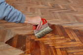 A man applying finish to a wood floor.