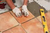 worker with gloves laying down tiles