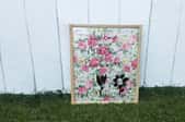 A dry erase board made with glass and floral paper in a frame.