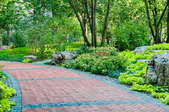 red paver walkway on a slight slope surrounded by greenery