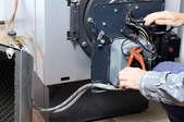hands repairing an oil furnace heating system