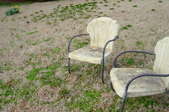 A dead lawn with retro chairs on it. 