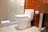 White toilet in a bathroom with a brick wall