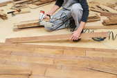 A man installs vinyl plank flooring.