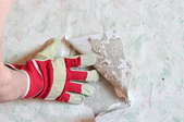 gloved hand peeling back wallpaper
