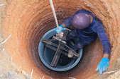 person in deep hole for water