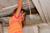 A little girl pushing an old attic door open with one hand.