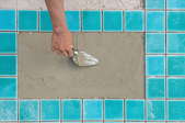 hand with tool laying aqua pool tiles