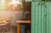 A green potting shed with gardening tools hanging around it.