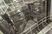 With the dishwasher open and the bottom rack pulled out, the lower dishwater spray arm can be seen.