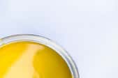 An off center, close-up shot of a can of yellow enamel paint.