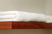 A wood shelf with white towels on it. 