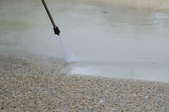 Power washing an exposed aggregate gravel driveway.