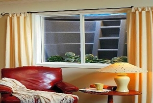A red, leather chair and a yellow lamp sitting in front of a basement egress window.