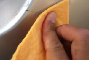 wiping a scratch on a car with a cloth