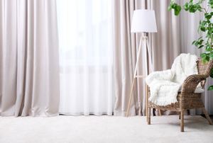A room with drapes, a chair, and a lamp.