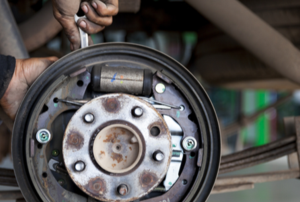 greasy hands using wrench to work on hydraulic brake behind cylinder