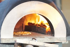 outdoor cement pizza oven with fire and pizza inside