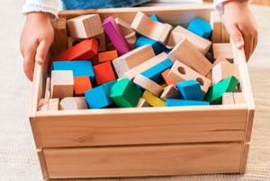hands holding box with wood toy blocks