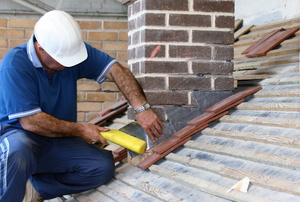 Man installing flashing around a chimney on a roof