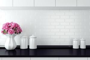 A black kitchen counter with a white backsplash and accessories.