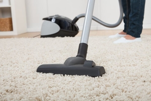 A vacuum cleaner being used to vacuum a carpet.