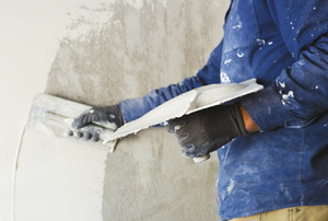 a person spreading stucco on a wall