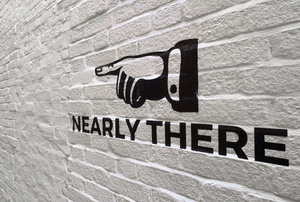 a brick wall with a hand pointing and text saying "nearly there"