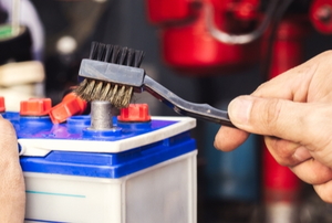 hand brushing the terminals of a car or boat battery clean