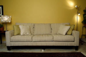 a tan sofa against a yellow wall with lamps on both sides of it.