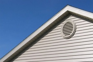 An oval soffit vent on the side of a roof.